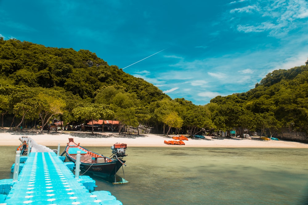 green boat beside blue wooden dock during daytime