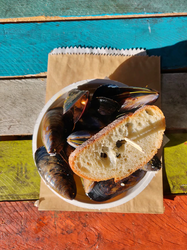 Close-up photo of a sizzling plate of spicy stuffed mussels with vibrant yellow and black background.
