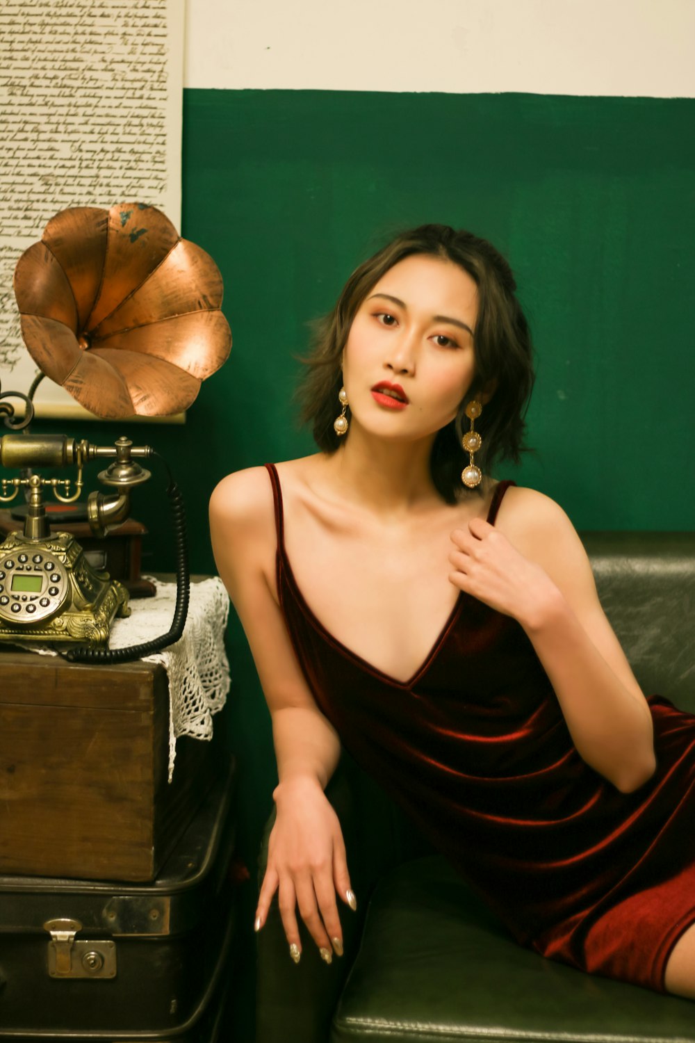 woman wearing red satin dress sitting on gray couch near brown gramophone