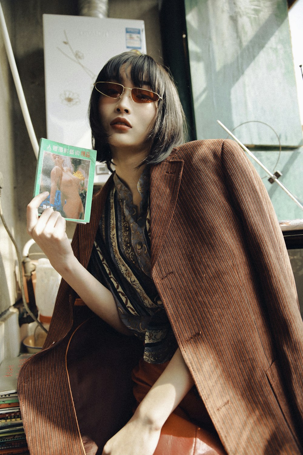 woman in brown coat holding green album