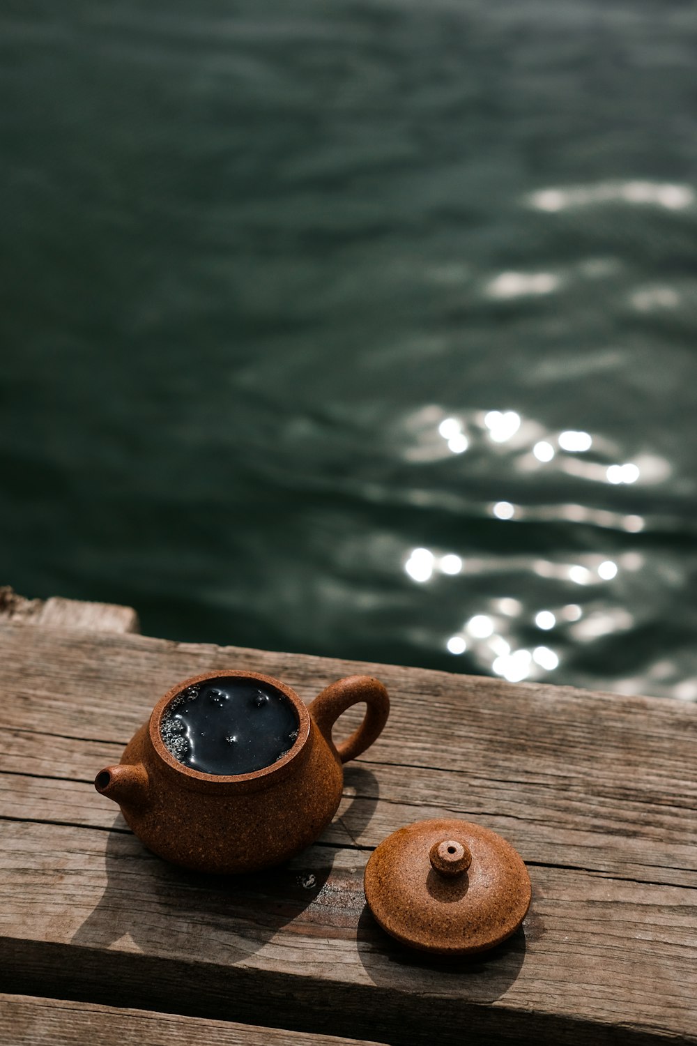 brown teapot near body of water close-up photography