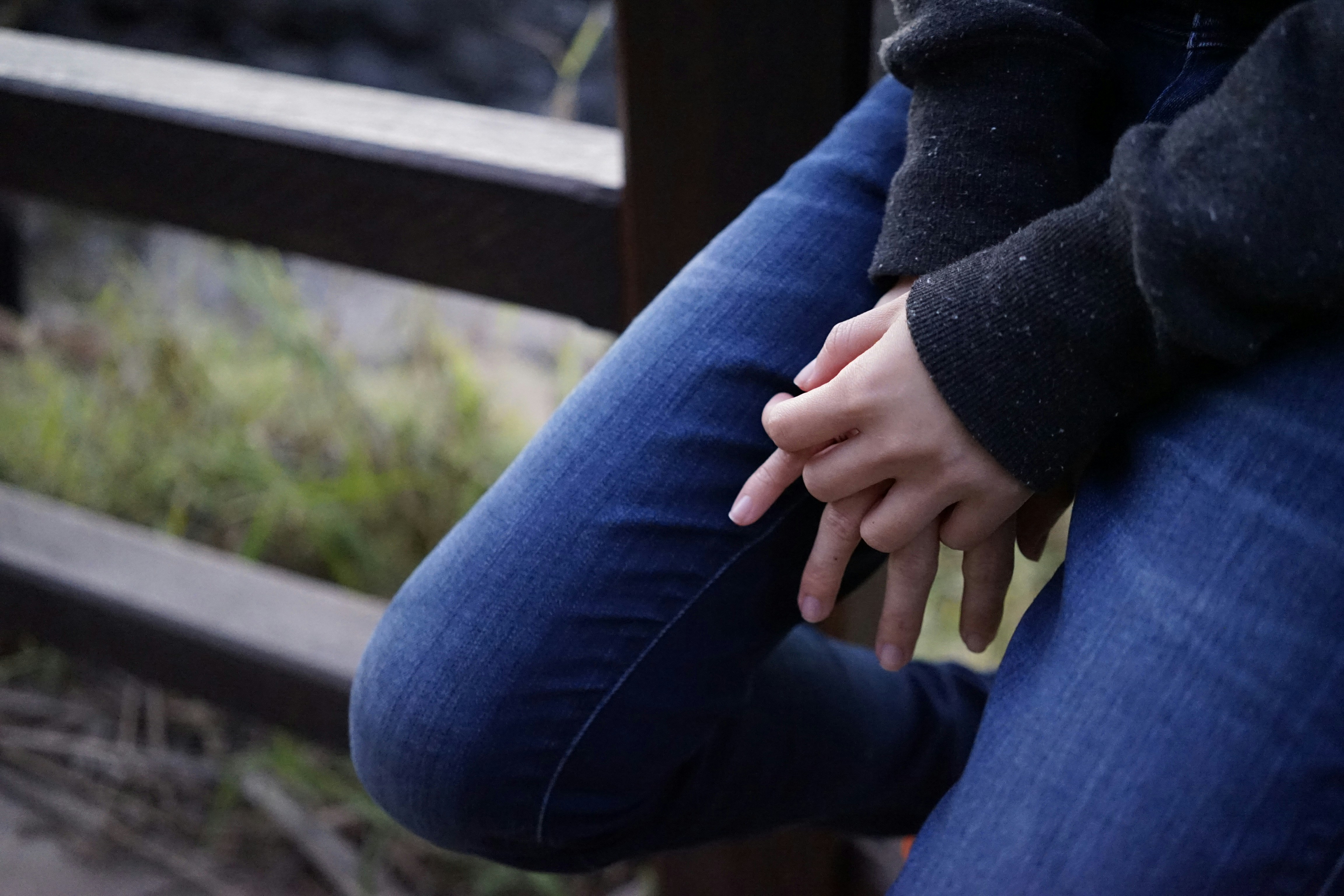 person sitting on wooden fence