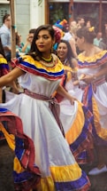 women wearing multicolored dresses dancing on street surrounded with people