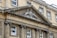 A historic stone building facade with classical architectural elements. An ornate pediment features a heraldic emblem and the inscription 'Royal Mineral Water Hospital'. Large, symmetrical windows are supported by decorative columns.