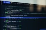 A computer screen displays a code editor with HTML code. The interface has a dark theme with syntax highlighting in various colors. Menu options like Inspector and Console are visible at the top.