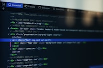 A computer screen displays a code editor with HTML code. The interface has a dark theme with syntax highlighting in various colors. Menu options like Inspector and Console are visible at the top.