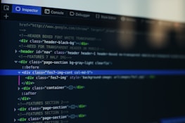 A computer screen displays a code editor with HTML code. The interface has a dark theme with syntax highlighting in various colors. Menu options like Inspector and Console are visible at the top.