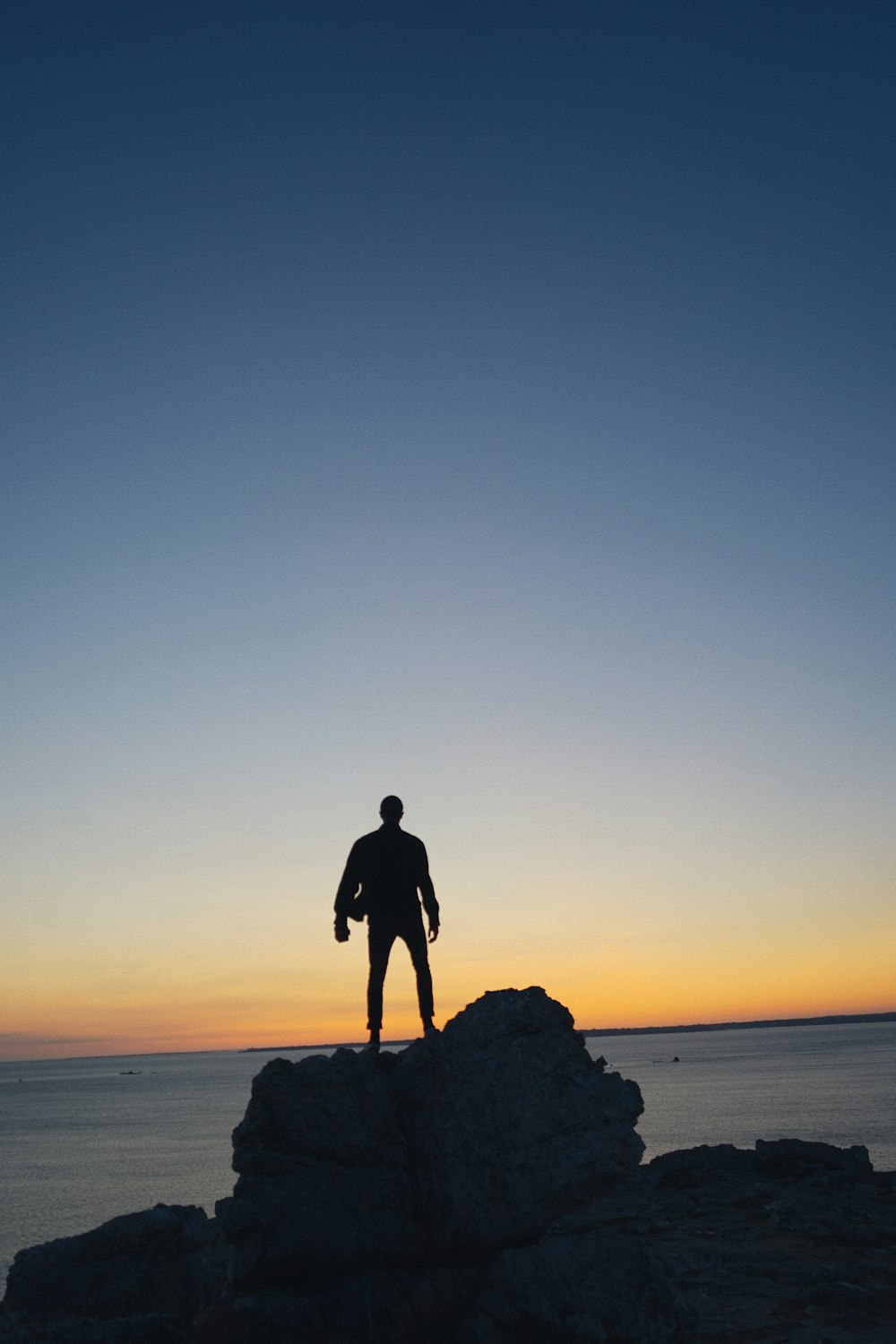 silhouette photography of person standing on rock