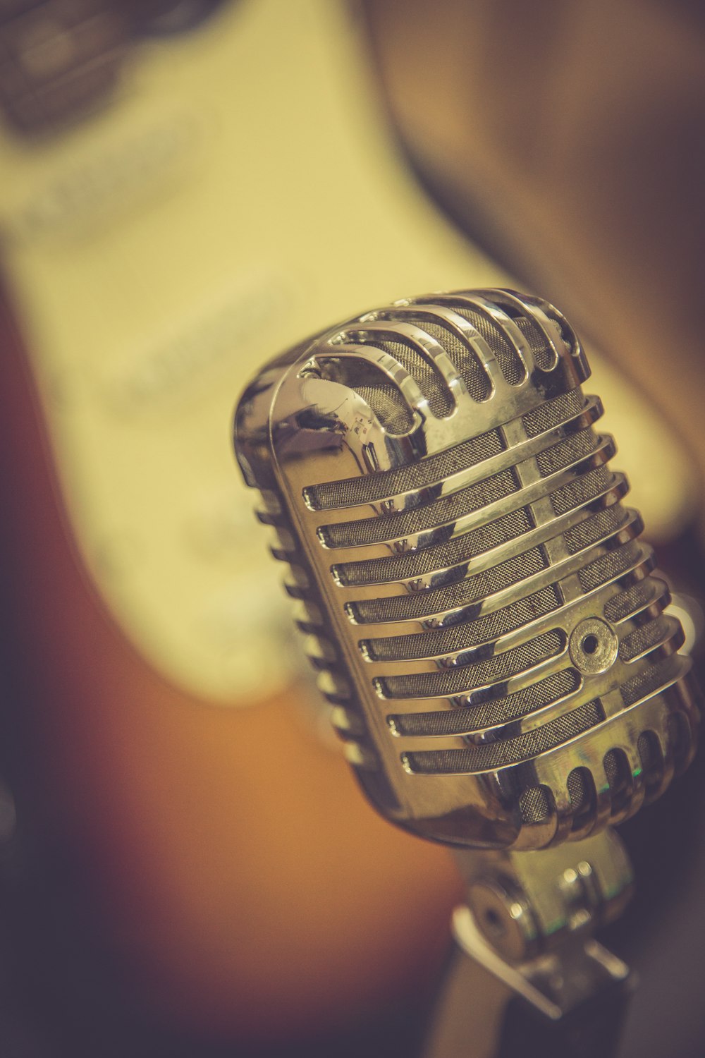 a close up of a microphone with a guitar in the background
