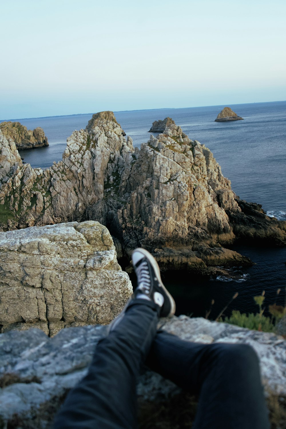 person sitting on black rock formation near body of water