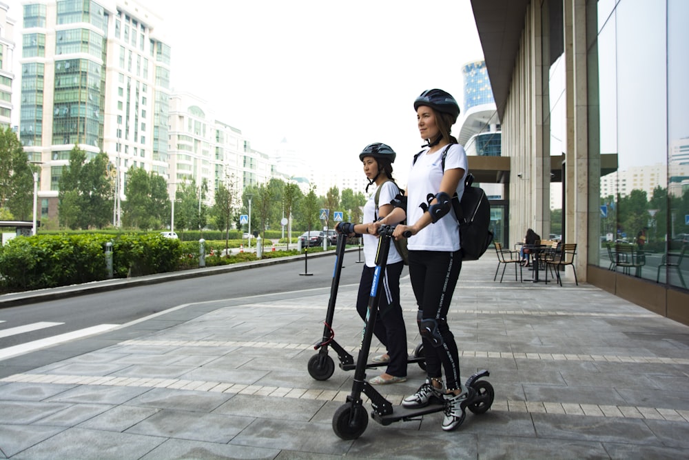 two women riding kick scooters