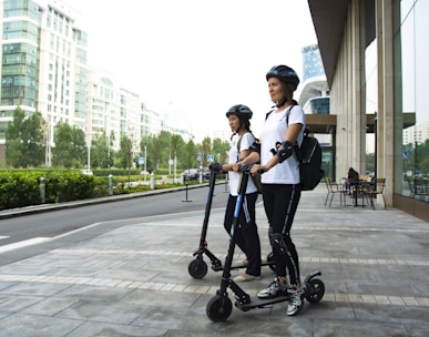 two women riding kick scooters