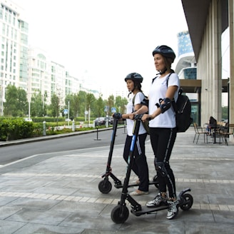two women riding kick scooters