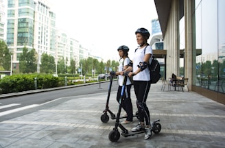 two women riding kick scooters