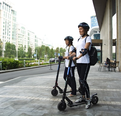 two women riding kick scooters