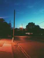 Solar-powered street lights illuminating a quiet neighborhood at dusk.