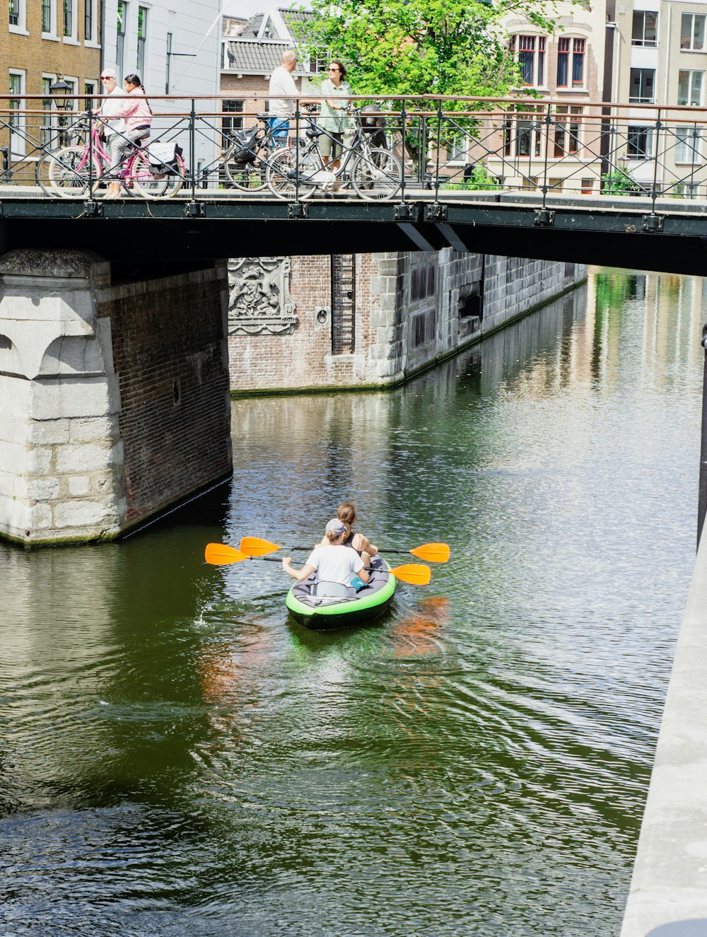 two people kayaking under bridge