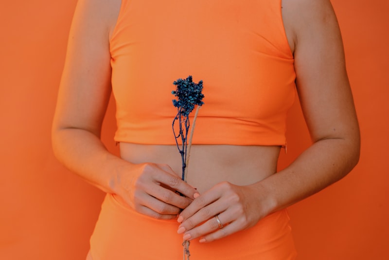 Woman wearing an orange top and orange pants holding a flower