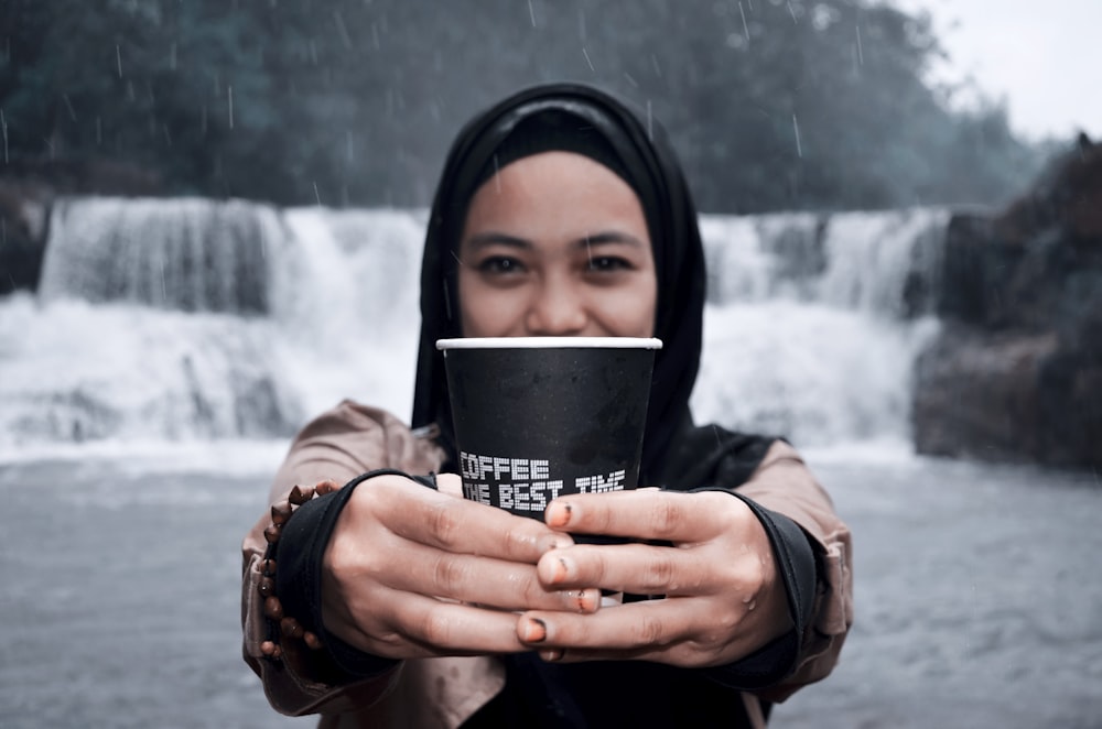 unknown person holding black cup outdoors