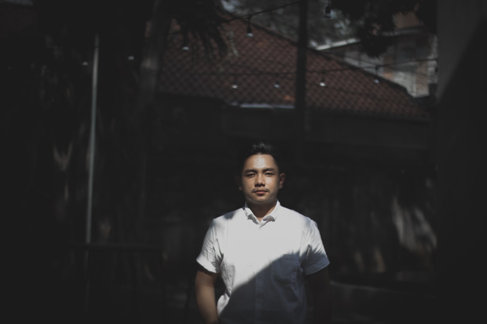 a man in a white shirt standing in front of a building