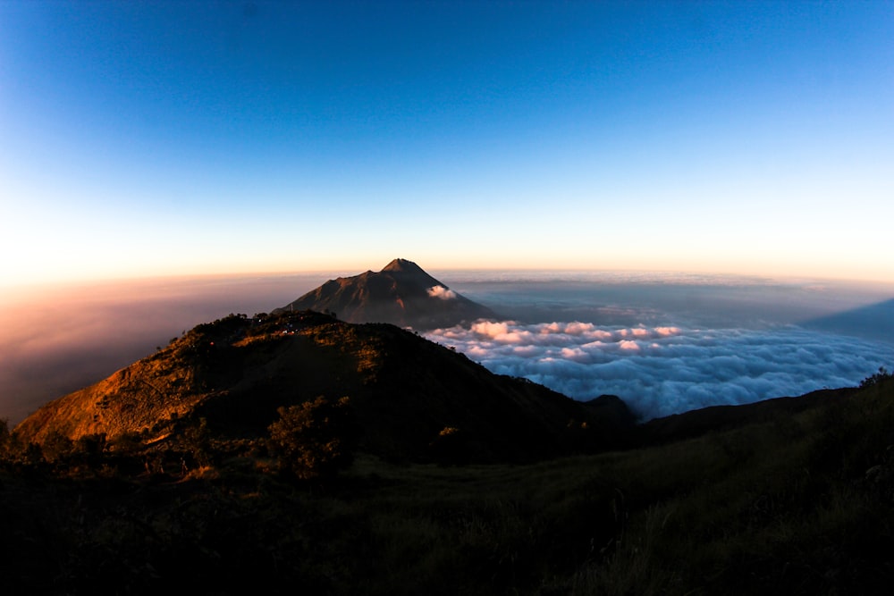 a view of the top of a mountain with clouds below