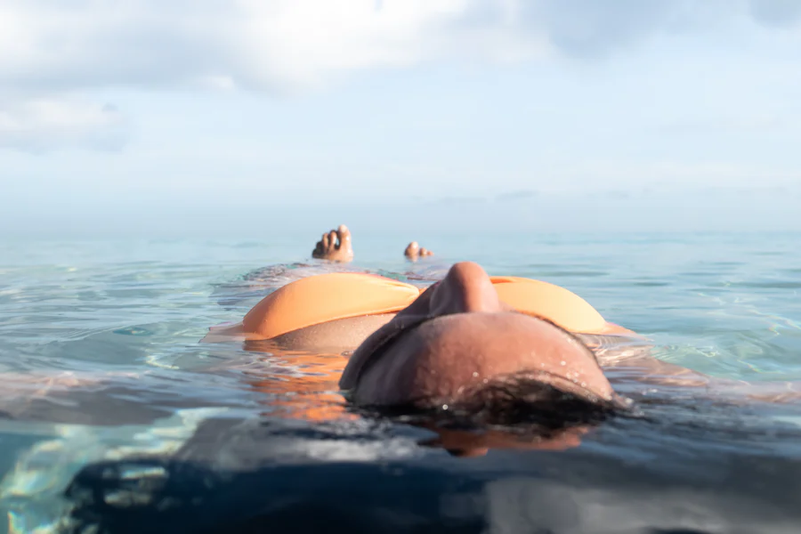 A person floating on their back in calm, clear ocean water.