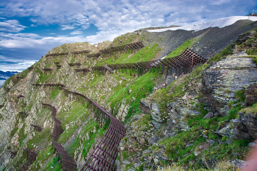 grass and rocky mountain with wooden pathway