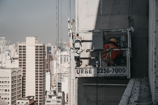 A skilled worker using akkora's suspension system on a tall building site, showcasing safety and efficiency.