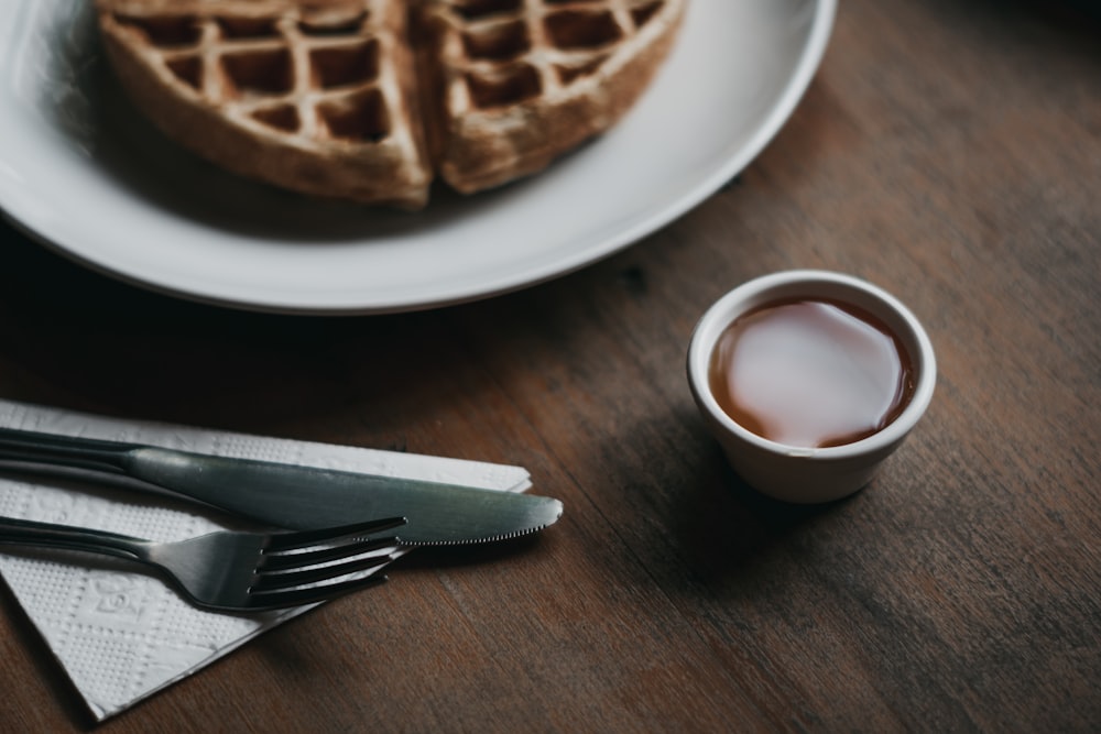 waffle on plate beside dip, fork, and knife