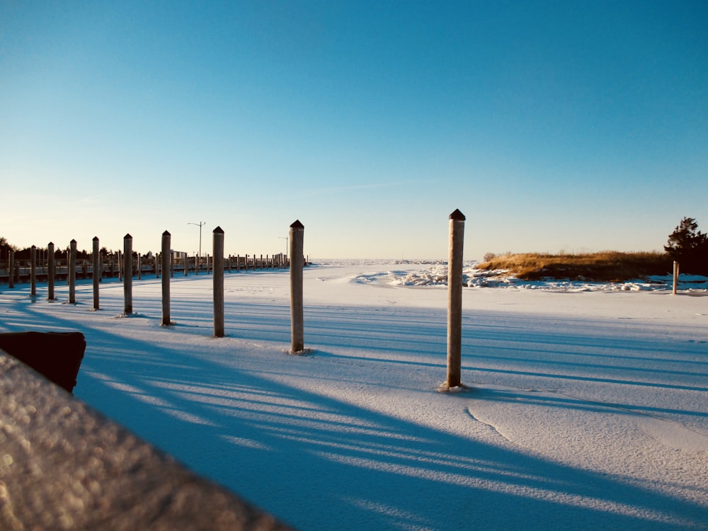 a row of poles sitting next to a snow covered field