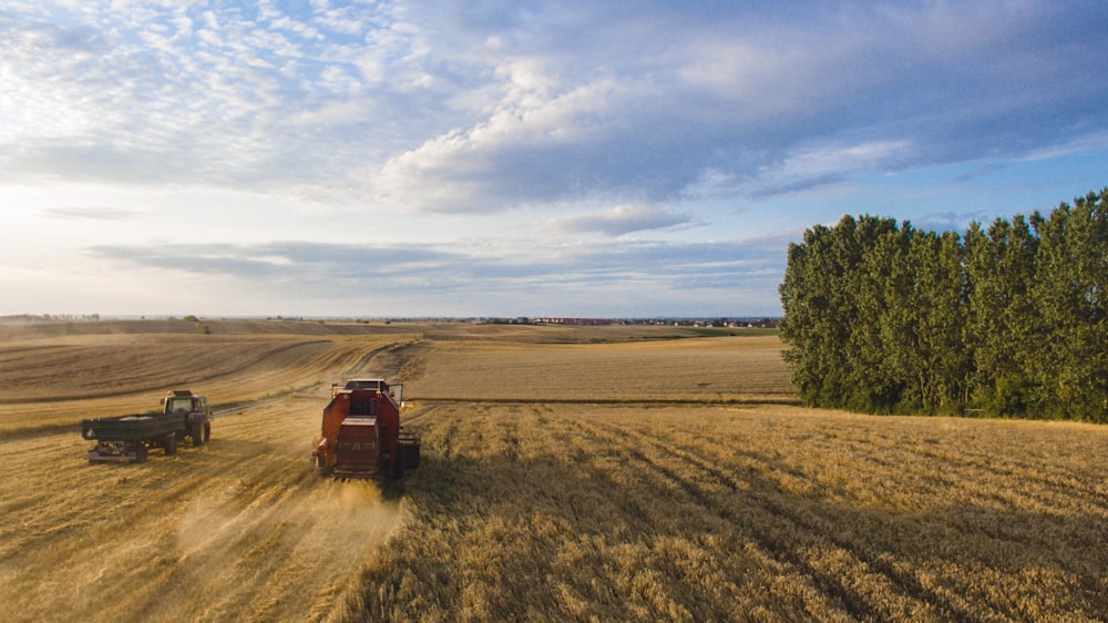 two green and red farm tractors on field under blue and grey cloudy sky