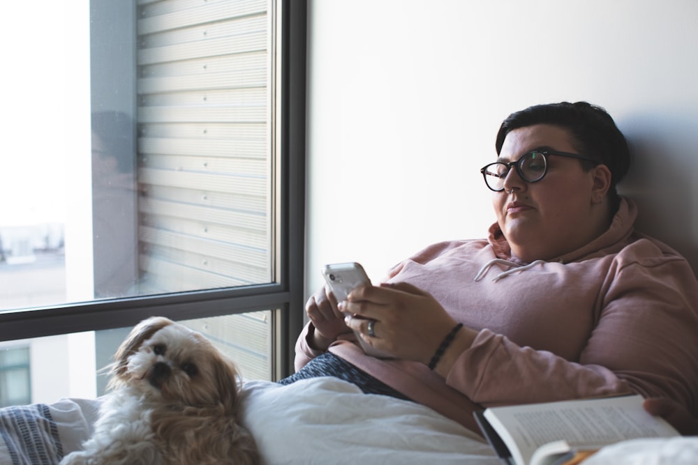 person holding smartphone beside dog