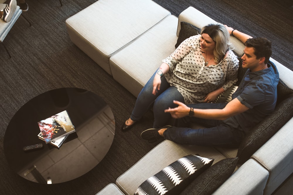 man and woman sitting beside each other on gray padded sectional sofa