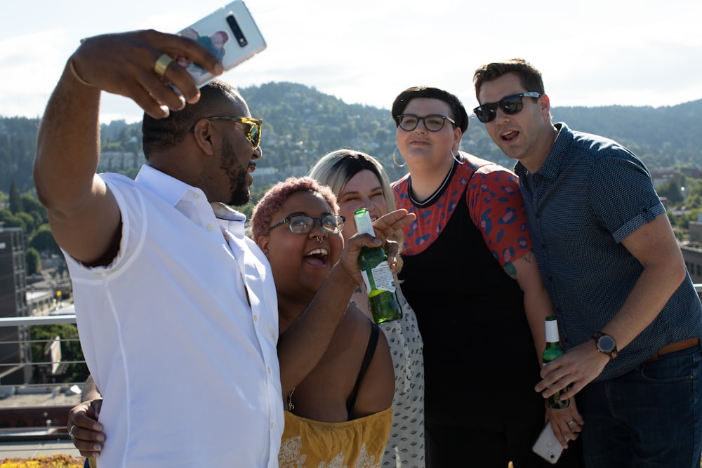 three women and two men standing while taking photo