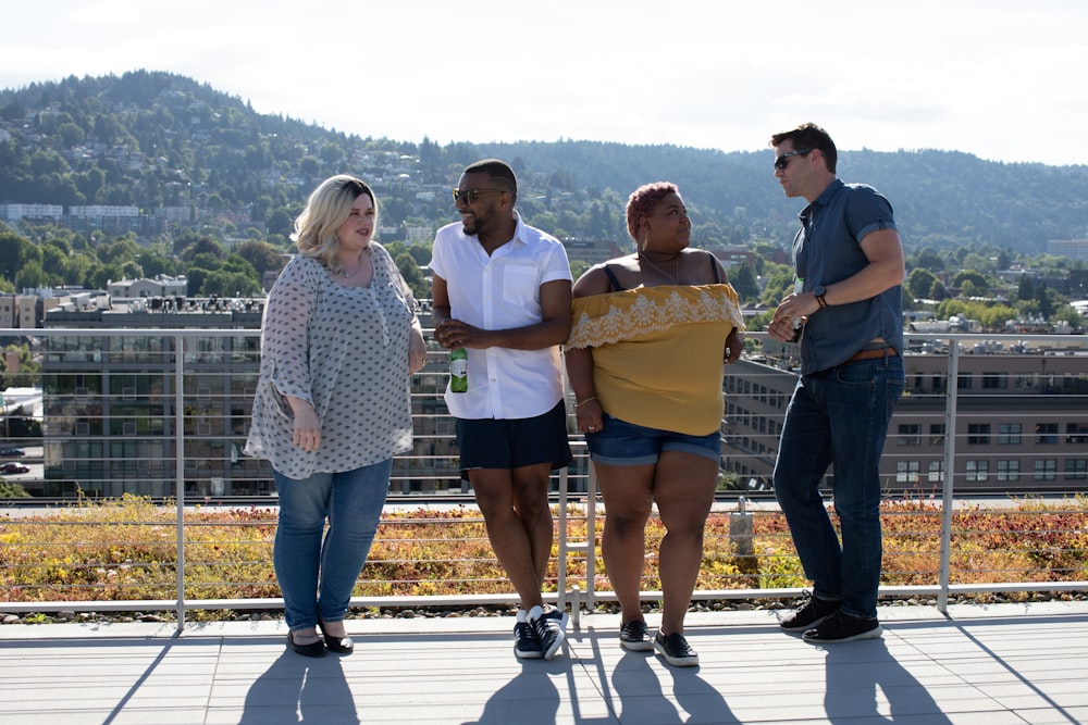 four people leaning on railings