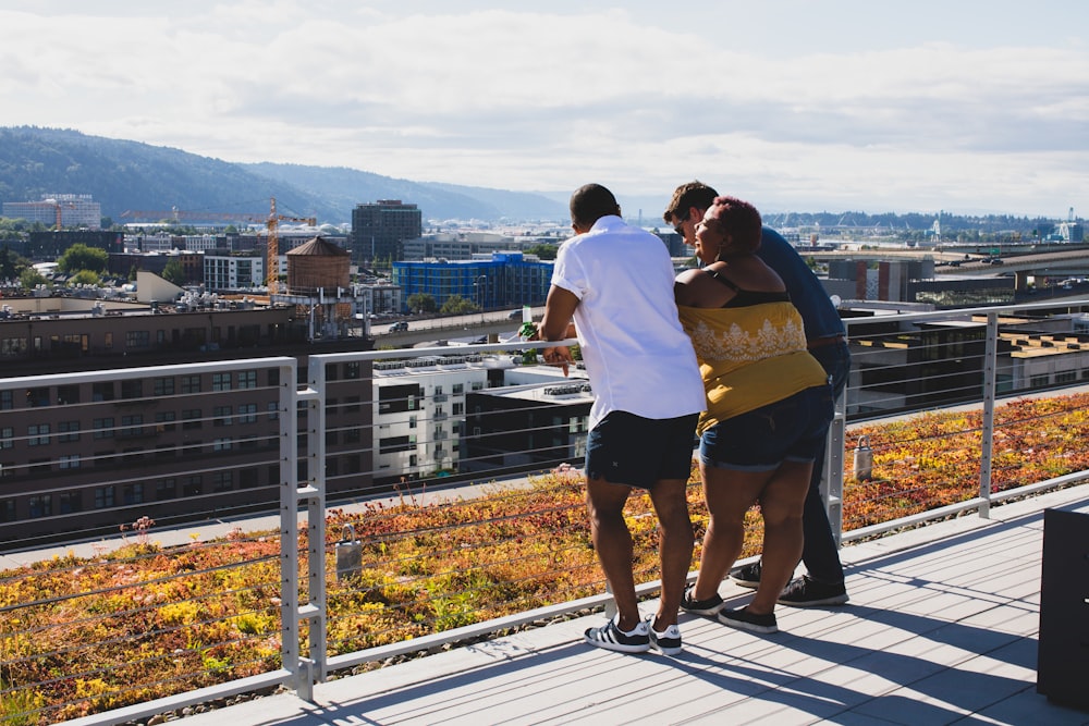 three people leaning on railing