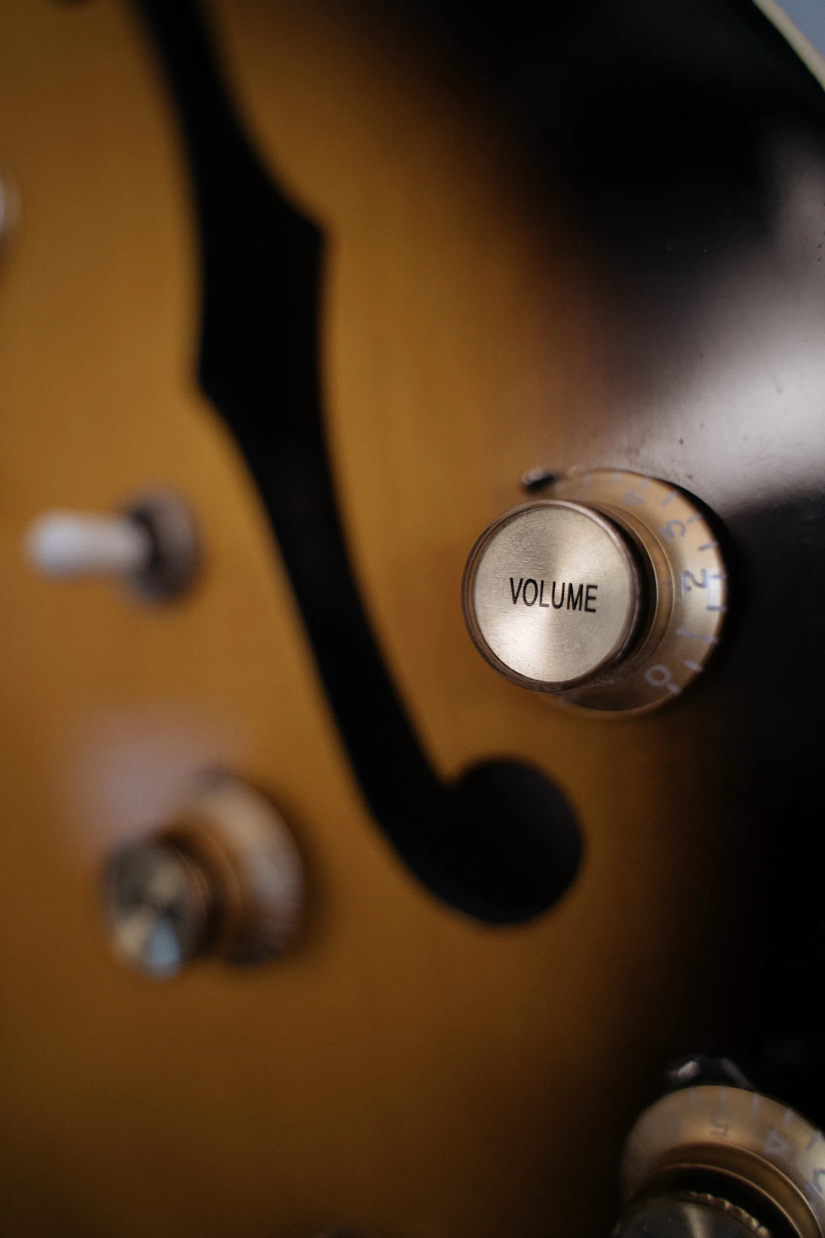 Close-up of a silver volume knob on a sunburst electric guitar