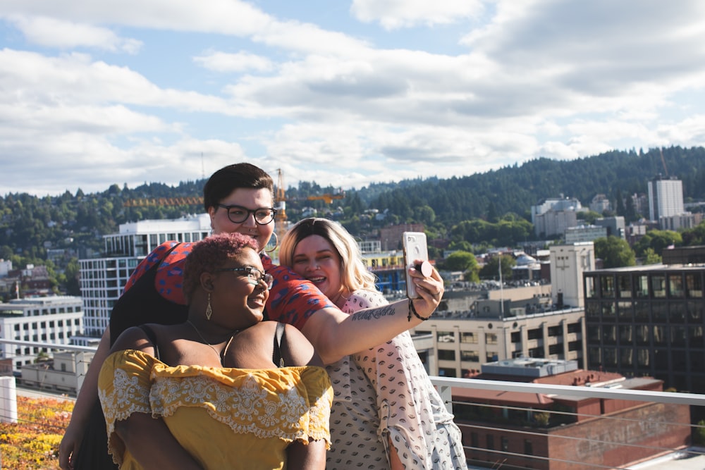 Three people taking a group selfie outdoors.