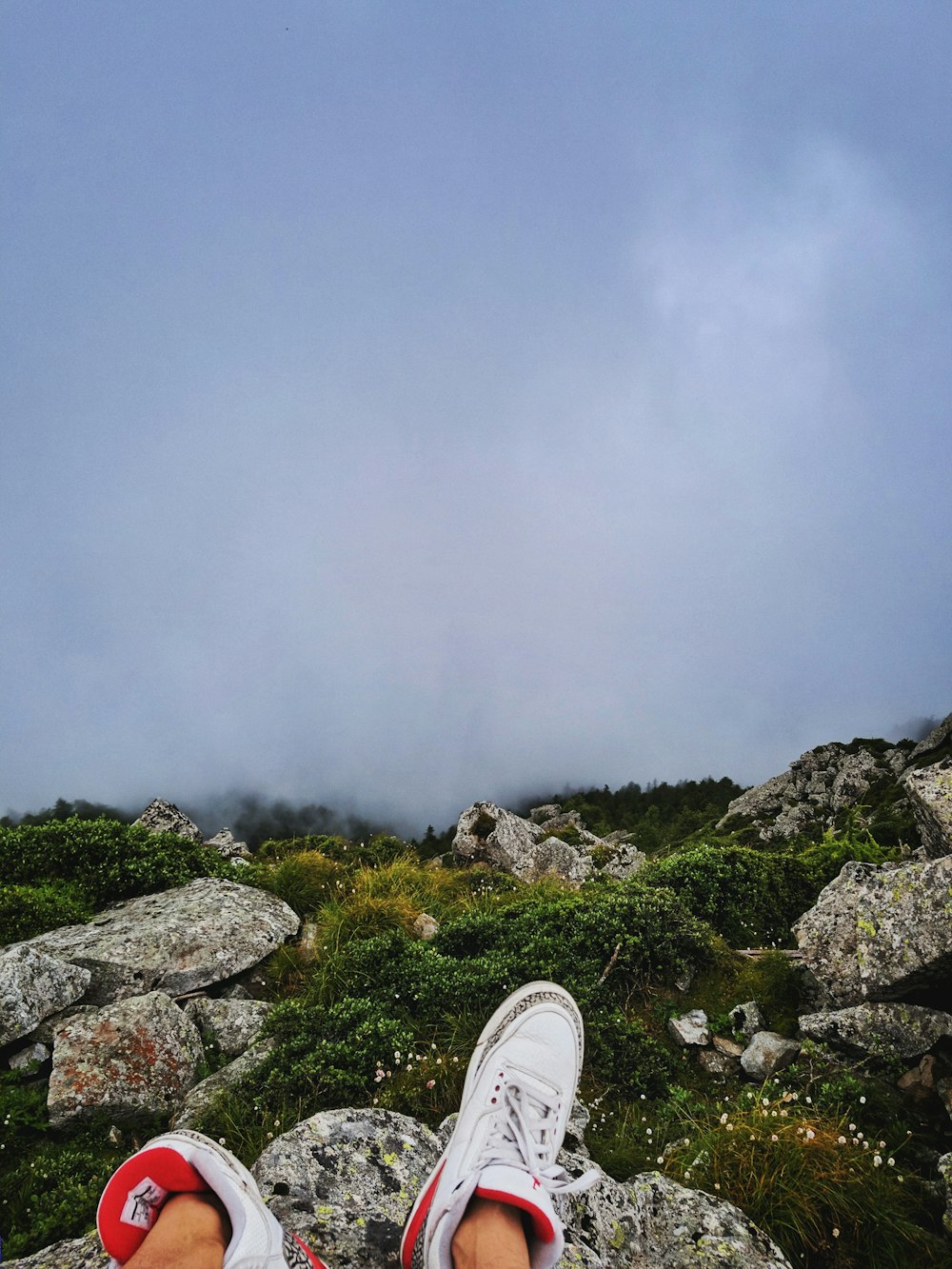 person sitting on rocky hill viewing fogs