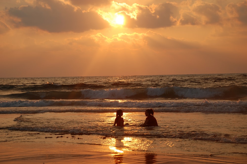 two people on a beach at sunset