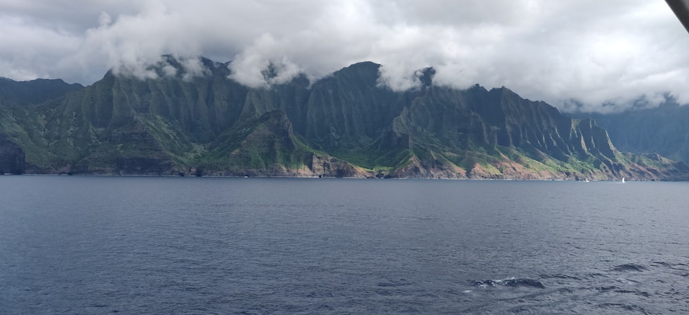 calm body of water beside cliff