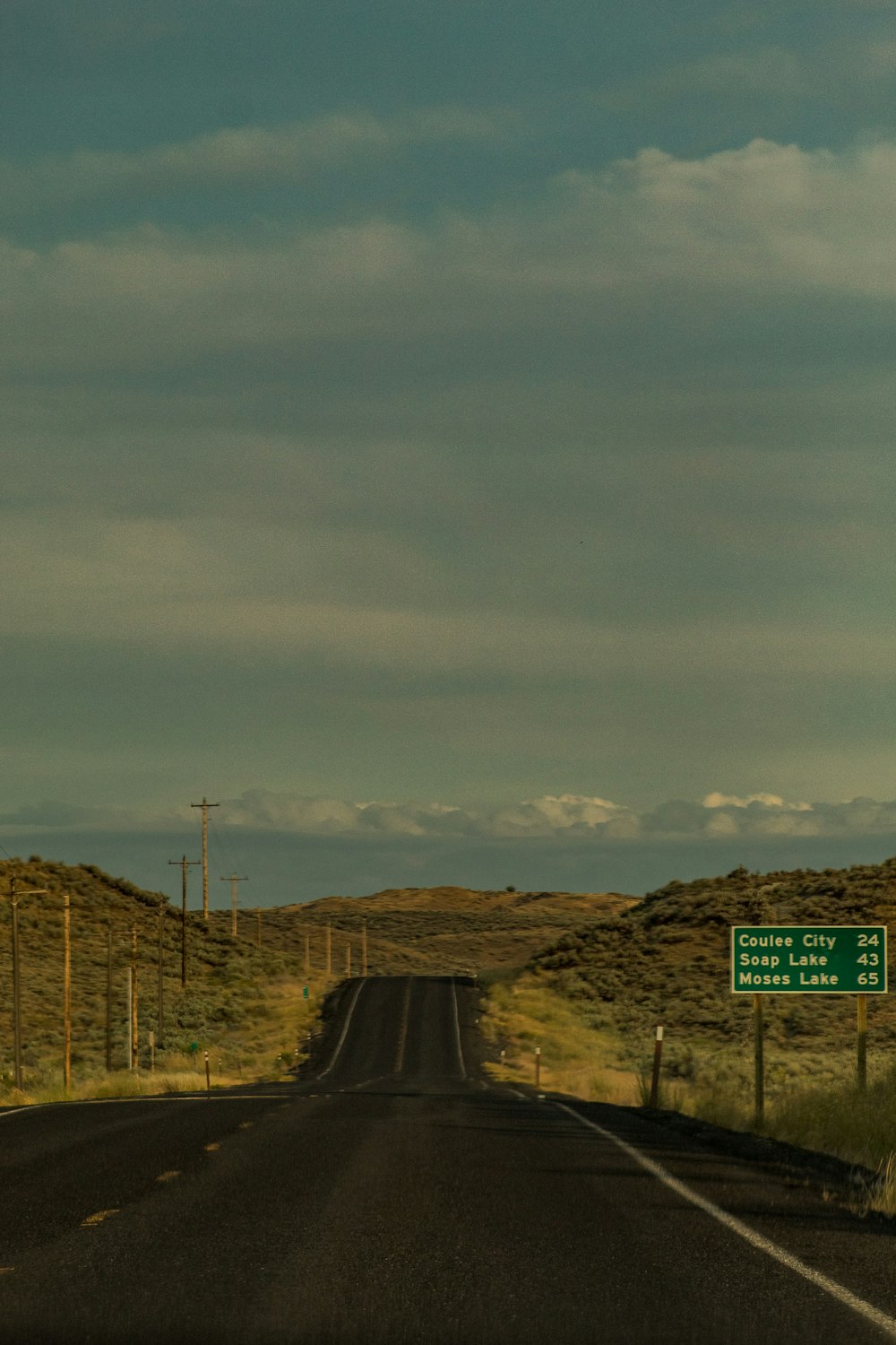 long straight concrete highway under white and blue cloudy sky