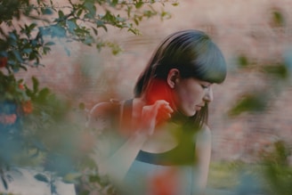 Portrait of a young woman surrounded by lush green foliage, captured with soft natural light.