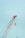 A red construction crane with a large hook hangs against a clear sky. The crane features a lattice boom design and is positioned at an angle with cables extending vertically.