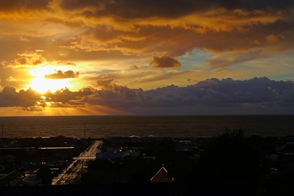 the sun is setting over a city by the ocean