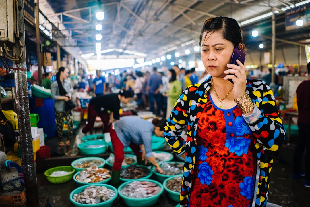 woman holding Android smartphone, Boss lady at a seafood market outside of Saigon