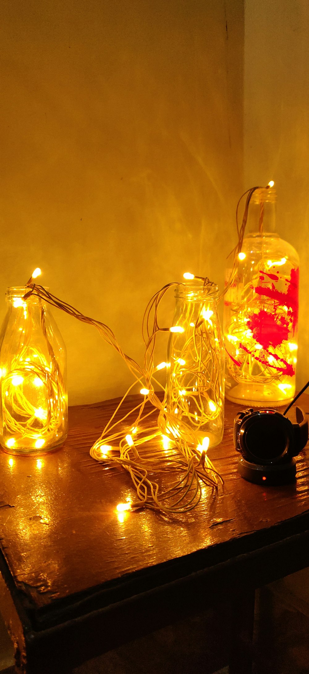 three clear glass bottles with yellow string lights
