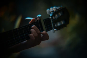 A close-up of the guitarist’s hands skillfully playing an acoustic guitar under soft, moody lighting.