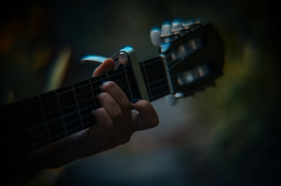 Close-up of falcke’s hands playing an acoustic guitar under soft lighting.