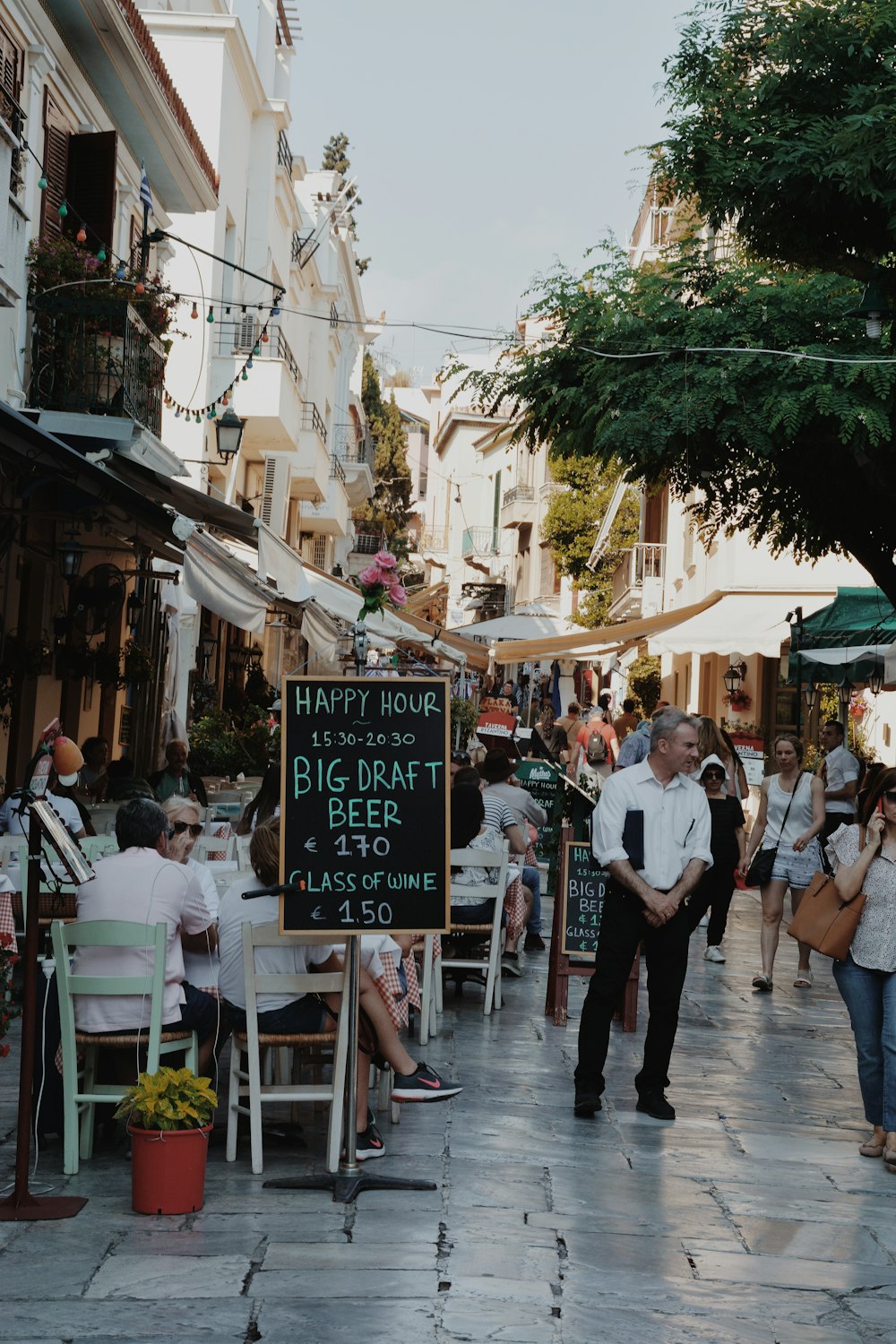 people walking near street and others sitting near coffee shop